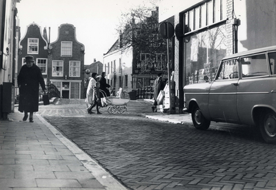 406571 Gezicht op de kruising van de Vrouwjuttenstraat (voorgrond) en de Oudegracht te Utrecht, met op de achtergrond ...